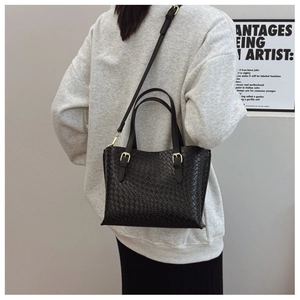 Detail of black woven texture shoulder bag with gold hardware and adjustable strap