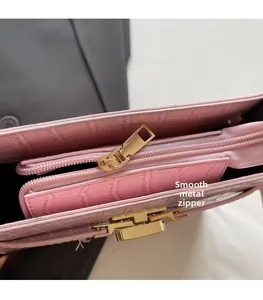 Detail of pink croc-embossed bag featuring a smooth gold zipper and metallic lock hardware
