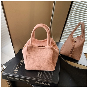Detailed macro view of pink litchi grain leather texture on a stylish mini handbag