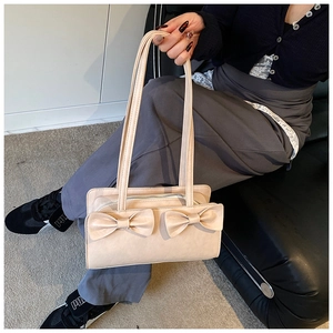 Detail of beige crossbody bag featuring dual aesthetic bows and secure zipper closure
