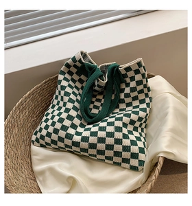 Vue de dessus d'un grand sac cabas en tricot à damier vert et blanc dans un panier