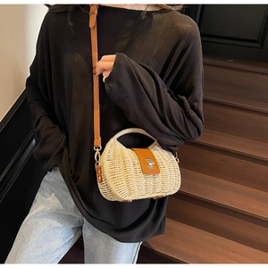 Straw mini crossbody bag with brown leather accents shown on a model against dark steps