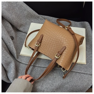 Detailed texture of brown faux crocodile leather bag with gold buckle hardware on a coat