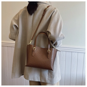 Brown crocodile texture shoulder bag styled on a model against a minimalist wall