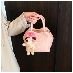 Detail of pink lychee textured crossbody bag with cute puppy plush charm decoration