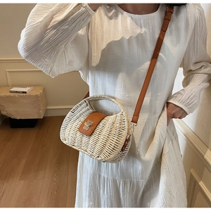 Detail of woven straw handbag featuring brown leather flap and silver twist lock closure