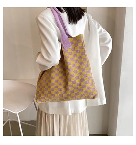 Sac fourre-tout en tricot à damier jaune et violet porté par un mannequin en blazer blanc