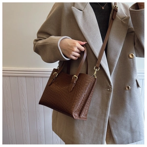 Detail of dark brown woven leather texture on a stylish crossbody shoulder bag