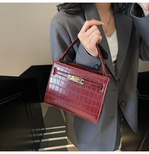 Macro detail of wine red crocodile embossed leather handbag with golden metal lock
