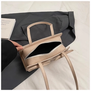Detail view of beige PU leather handbag with elegant bow decoration and zipper closure