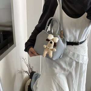 Detail of light blue leather mini tote bag with cute puppy plush charm and gold hardware