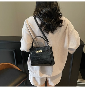 Detailed view of black crocodile pattern leather handbag with gold metal hardware buckle