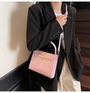 Detail of pink croc-effect small handbag with gold buckle worn by model in suit
