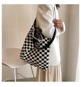 Détail du grand sac cabas en tricot à damier noir et blanc porté par un mannequin