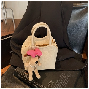 Detail of cream lychee texture leather handbag with cute puppy plush charm accessory
