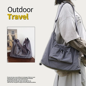 Detail of grey large capacity tote bag featuring functional drawstring front pocket