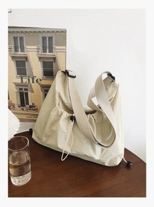 Detail of minimalist cream tote bag with adjustable drawstring and wide woven strap
