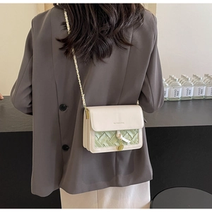 Detail of crossbody bag with beige leather and green woven panel on model back