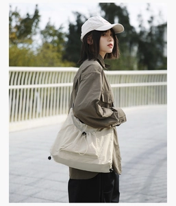 Close-up of a cream drawstring tote bag paired with a vintage brown plaid shirt in a street setting