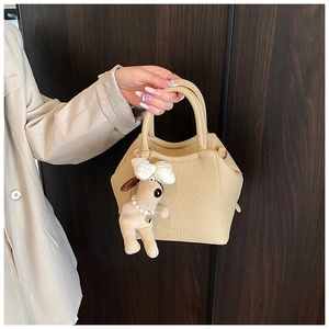 Detail of beige lychee texture handbag with cute puppy plush charm and logo