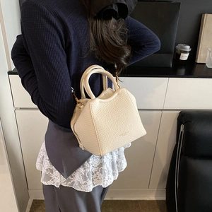 Detail of cream leather shoulder bag featuring gold hardware and logo on textured finish