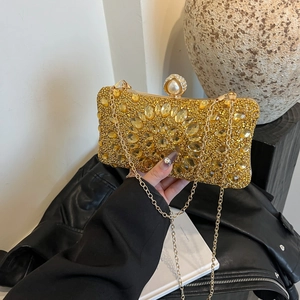 Sparkling gold evening clutch with rhinestones, pearls and chain strap held by model