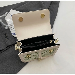 Detail view of beige shoulder bag with green velvet quilting and interior storage layers