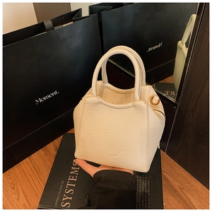 Detail of cream white tote bag with pebble leather texture and gold side zipper detail