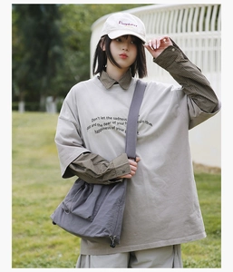 Detail of dark grey utility messenger bag paired with a layered oversized tee and cap