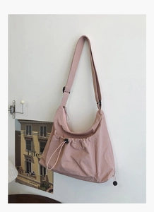 Detail of adjustable strap and drawstring pocket on pink nylon tote crossbody bag