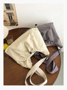 Detail of minimalist nylon tote bags featuring drawstring pockets and adjustable straps