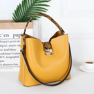 Detail of yellow bucket bag with snake-embossed leather strap and gold buckle