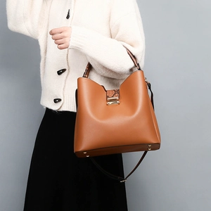 Detail view of brown PU leather bag with snake pattern handle and metal protective feet