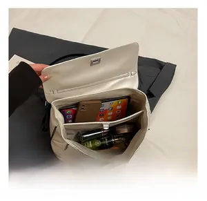 Detailed interior of a beige underarm tote bag showing organized multi-layer storage capacity