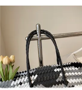 Detail of tricolor woven tote bag with checkerboard pattern on chrome display stand