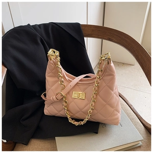 Détail du sac bandoulière rose matelassé avec chaîne dorée et fermoir sur chaise bois