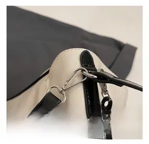 Detailed macro view of silver metal hook and strap on beige and black tote bag