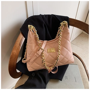 Détail du sac matelassé rose avec chaîne dorée posé sur une chaise en bois élégante