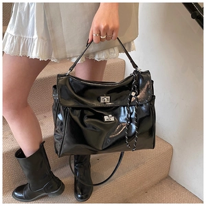 Detail of black patent leather tote bag with silver twist lock and braided rope ornament