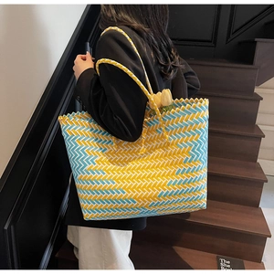 Detail of woven tote bag with yellow and blue chevron pattern carried on stairs