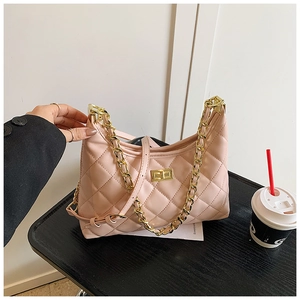 Détail d'un sac en cuir rose matelassé avec chaîne dorée et fermoir rotatif doré