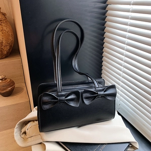 Minimalist black rectangle handbag featuring dual bow accents and long handles for shoulder wear