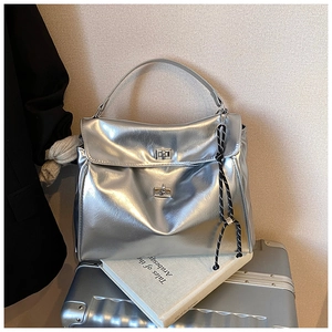 Detailed close-up of metallic silver pleated tote bag with twist-lock closures and rope charm