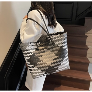 Detailed side view of large woven tote bag with grey geometric patterns on model