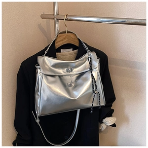Detail of silver metallic tote bag featuring dual twist locks and striped side ropes