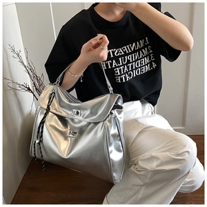 Detail of silver metallic tote bag featuring double metal twist-lock closures and rope accent