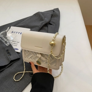 Beige quilted shoulder bag with gold chain strap and spherical charm for a chic look