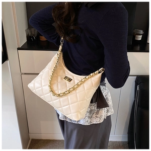Détail d'un sac demi-lune blanc matelassé avec chaîne dorée et fermoir tournant métal