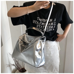 Silver metallic tote bag with flip lock shown on shoulder for a stylish commuter look