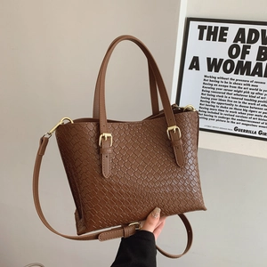 Brown woven crossbody underarm bag with gold hardware and adjustable strap in minimalist room